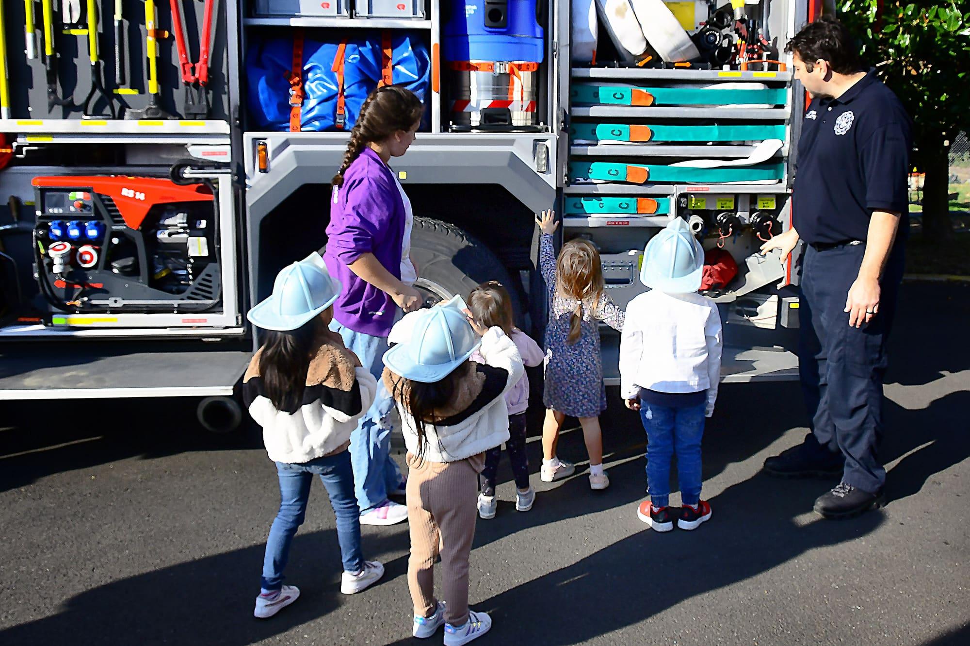 Children in toy fire helmets touring a fire engine